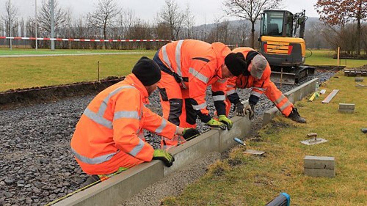 Mitarbeiter des städtischen Bauhofes setzen Borden an der neuen Wurfanlage neben dem Kunstrasenplatz. Foto: Alexander Stemplewitz