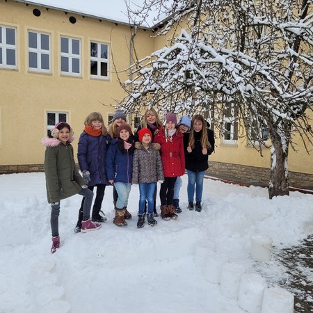 Mädchen der Klassenstufen 1 und 4 bauen sich eine Terrasse aus Schnee