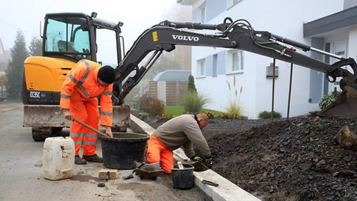 Mitarbeiter Chris Wuppinger und Mike Muche vom städtischen Bauhof bei der Einbringung der Muldenrinnen in der Zeigerheimer Straße. Foto: Alexander Stemplewitz