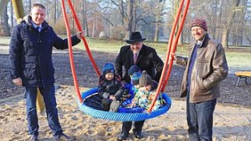 Michael Habeck, Bürgermeister Jörg Reichl und Mathias Bemm (v.l.n.r.) mit Kindern des Kindergartens Sputnik an einem der Spielgeräte im Heinepark. Foto: Alexander Stemplewitz