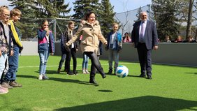 Stellvertretend gibt Lehrerin Diana Enders im Beisein von Bürgermeister Jörg Reichl und ihrer Klasse den Anstoß zur Eröffnung des neuen Minispielfelds in der Grundschule Schwarza.