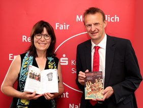 Festivaldirektorin Petra Rottschalk und Sparkassen-Vorstandsvorsitzender Martin Bayer präsentieren das druckfrische Programmheft zum diesjährigen Rudolstadt-Festival. Foto: Tom Demuth