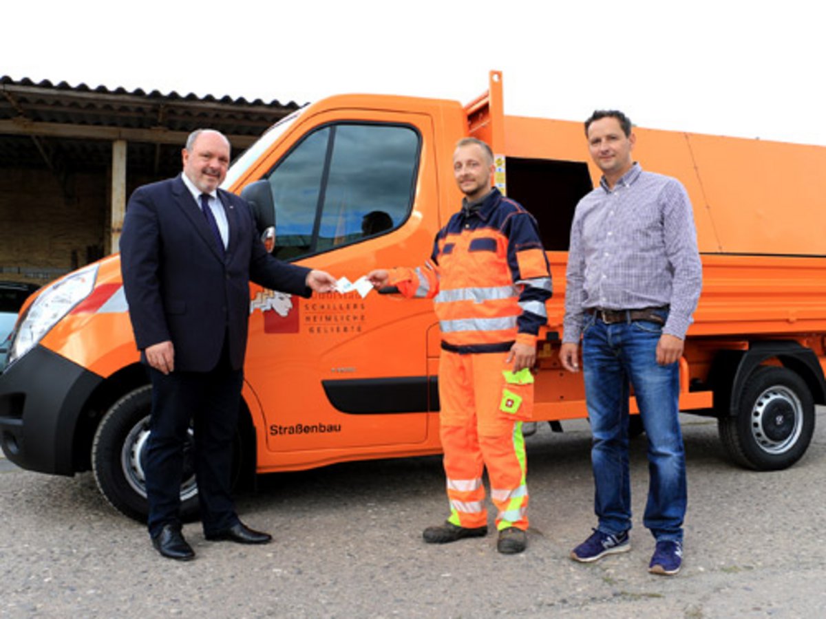 Bürgermeister Jörg Reichl übergibt Bauhof-Mitarbeiter David Meyer und Bauhof-Leiter Daniel Warnke symbolisch den Fahrzeugschein des neuen Müllentsorgungsfahrzeugs. Foto: Tom Demuth