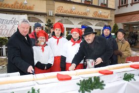 Stadtringvorsitzender Lutz Schmidt und Bürgermeister Jörg Reichl beim Anschneiden der Biskuitrolle vor dem Café Brömel