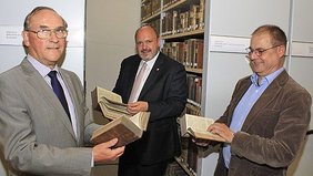 Foto: Der Vorsitzende des Gemeindekirchenrates Dr. Eberhard Rau, Bürgermeister Jörg Reichl und Superintendent Peter Taeger beim Durchstöbern der nun in der Historischen Bibliothek aufbewahrten Bücher