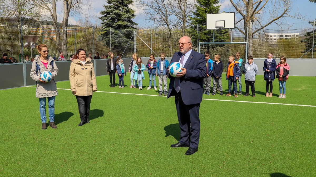 Bürgermeister Jörg Reichl (r.) und Fachdienstleiterin für Bau und Umwelt Annett Giesel (l.) übergeben neues Minispielfeld stellvertretend an Lehrerin Diana Enders und ihre Klasse. 