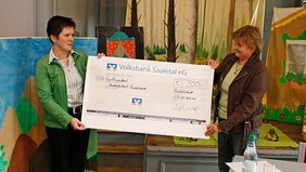 Bild: Annett Zimmermann von der Volksbank Saaletal eG überreicht Angela Hansen von der Stadtbibliothek Rudolstadt den symbolischen Scheck in Höhe von 500 Euro.