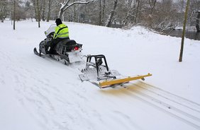 Foto: Ein Mitarbeiter von der Firma Abschlepp- und Bergedienst Schmidt zieht im Heinepark am Saale-Ufer die Ski-Loipe